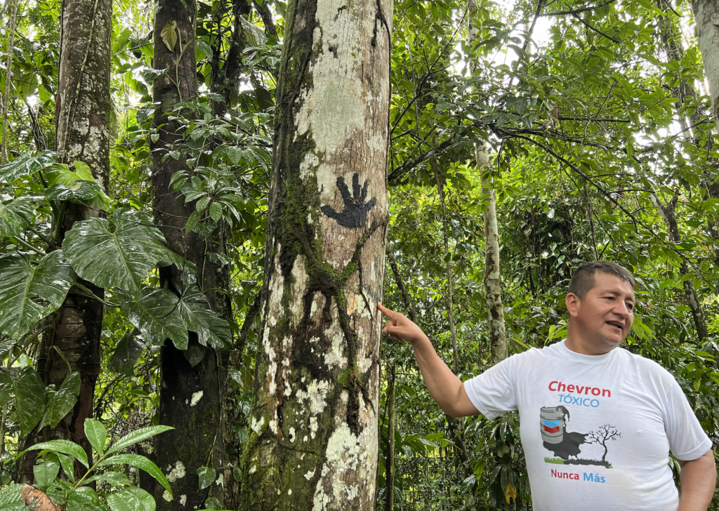 Donald Moncayo, president of The Union of People Affected by Texaco, stands next to an oil stained handprint at a former Texaco drilling site in the province of Sucumbíos, Ecuador on Aug. 11, 2022. Credit: Katie Surma/Inside Climate News