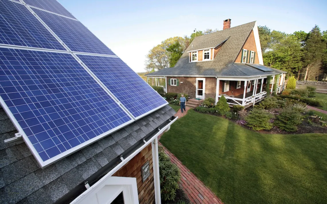 Len Bicknell caminha de sua casa para sua garagem, onde seus painéis de energia solar são montados no telhado em Marshfield, Massachusetts. Os interesses energéticos renováveis estão flexionando sua nova energia não apenas com painéis solares e turbinas eólicas, mas nos corredores da casa de Massachusetts.