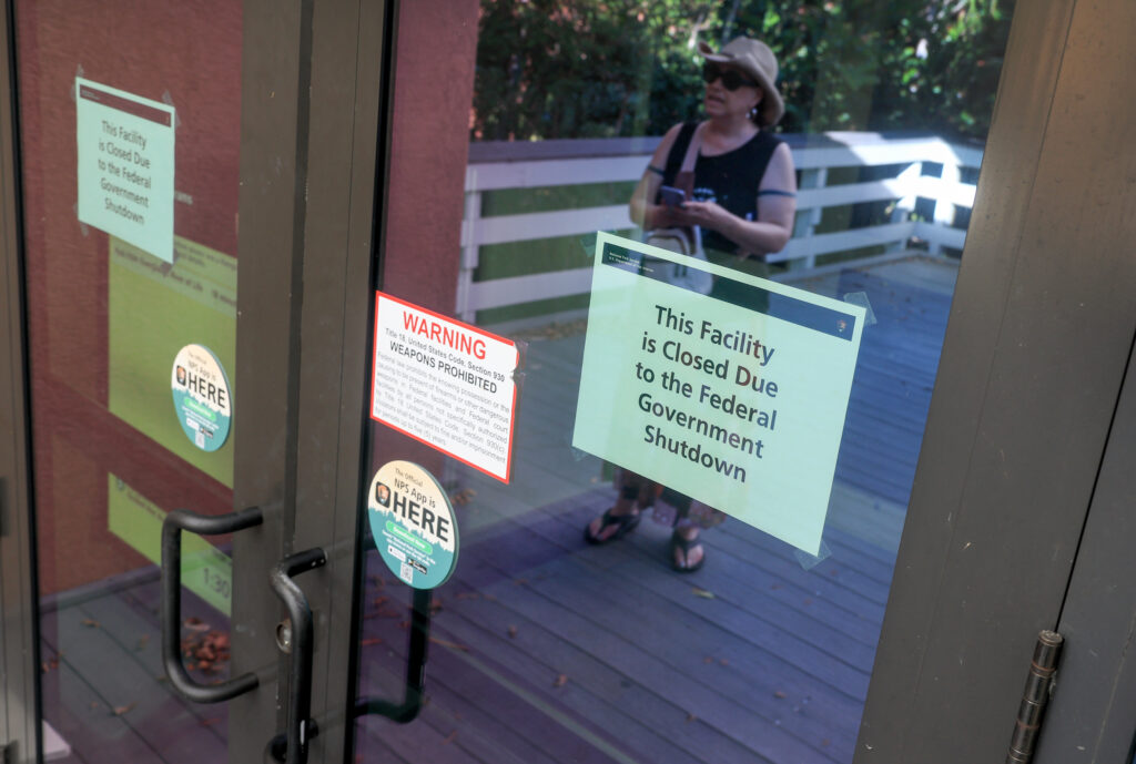 Susanne Brown, from Bellingham, Wash., looks at a sign that reads, “This Facility is Closed Due to the Federal Government Shutdown,” on the door to an Everglades National Park visitor center on Wednesday in Florida. Credit: Joe Raedle/Getty Images
