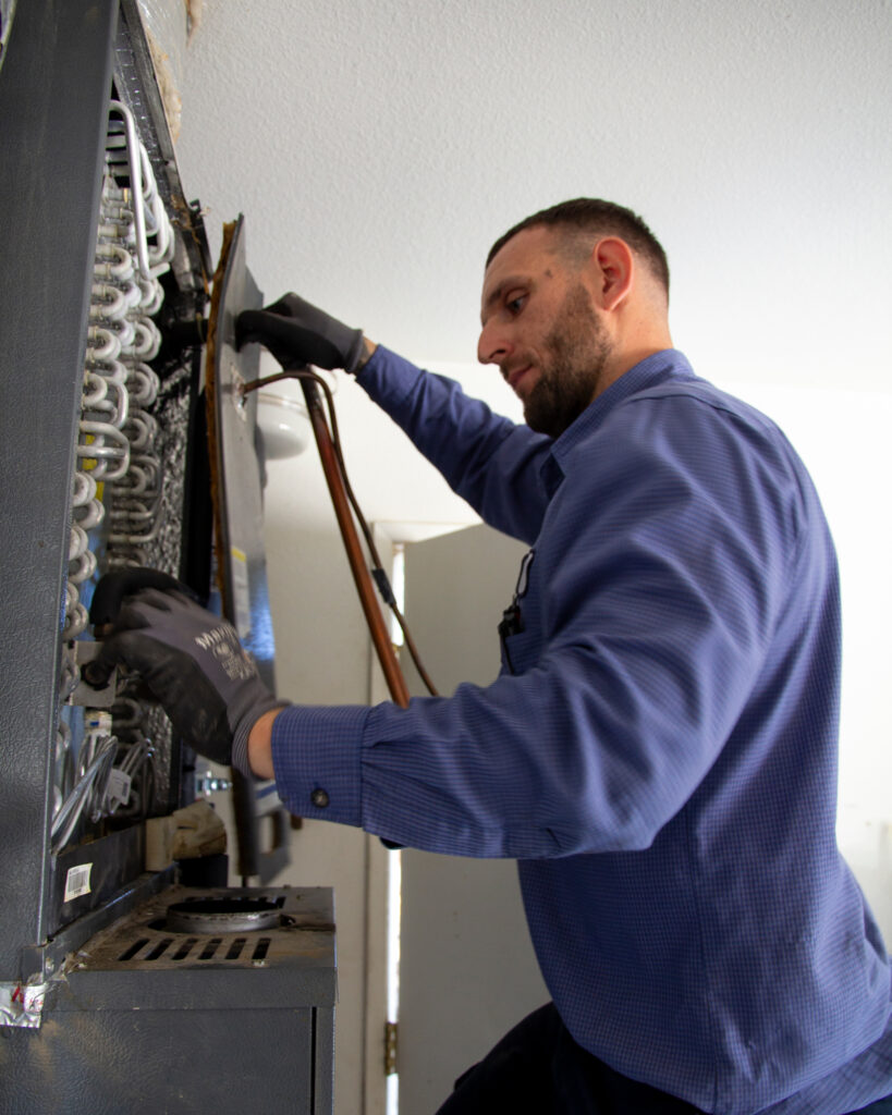 Um técnico da John Harrison Contracting remove um sistema HVAC movido a gás antes de instalar uma bomba de calor para a casa de Vasquez. Crédito: Twilight Greenaway/Naturlink