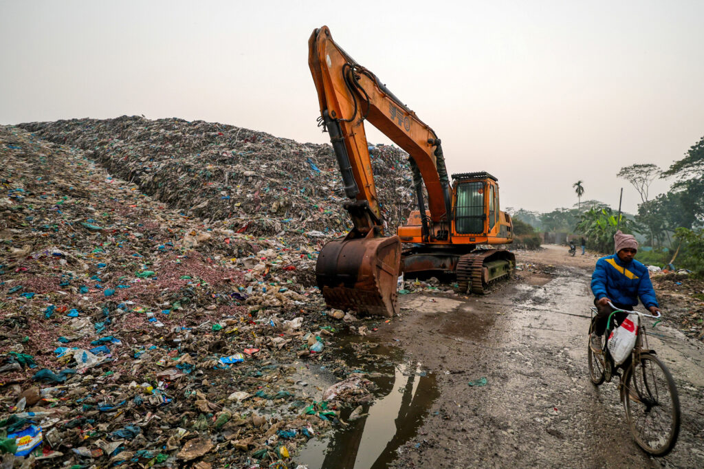 A cyclist passes a landfill, a known emitter of Methane, on Jan. 21 in Barisal, Bangladesh. Credit: Niamul Rifat/Anadolu via Getty Images