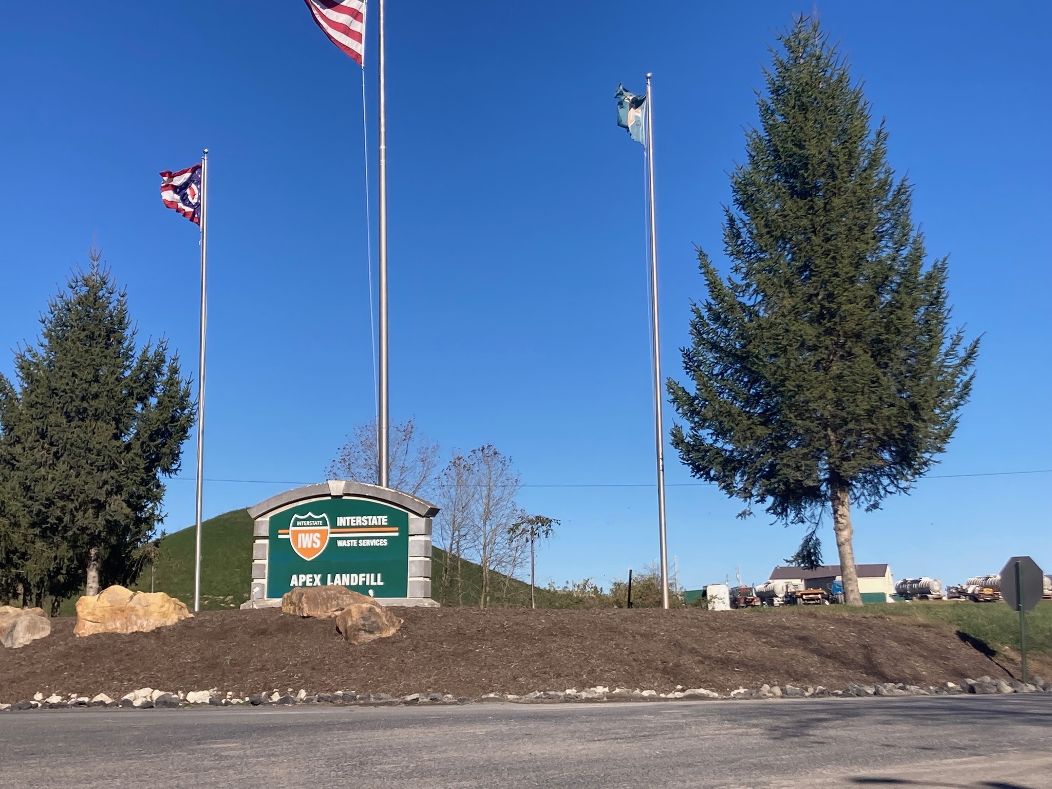 Image shows the Apex landfill exterior sign with flags above it