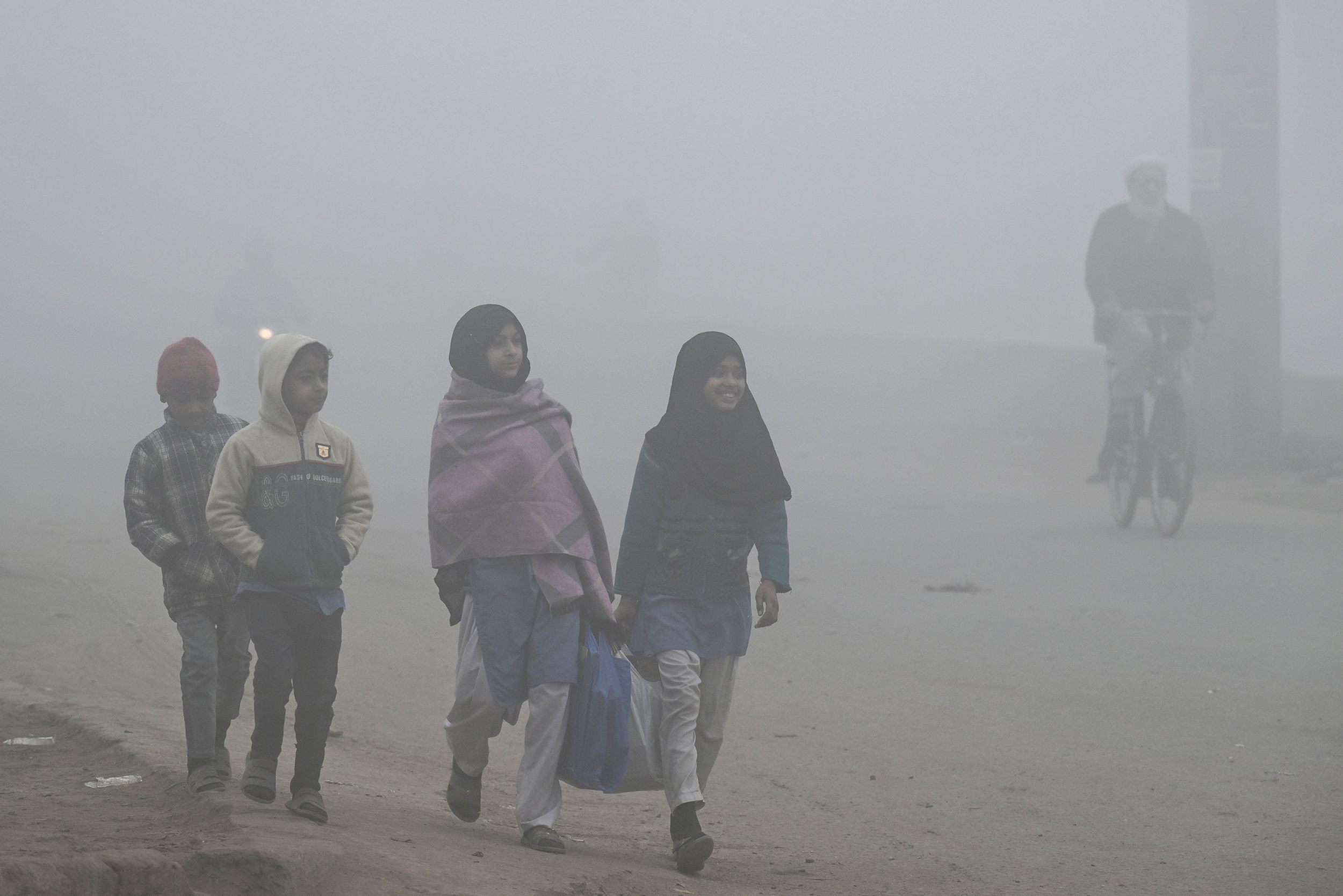 Crianças caminham para a escola em meio à densa poluição atmosférica em Lahore, em 16 de dezembro. Crédito: Arif Ali/AFP via Getty Images
