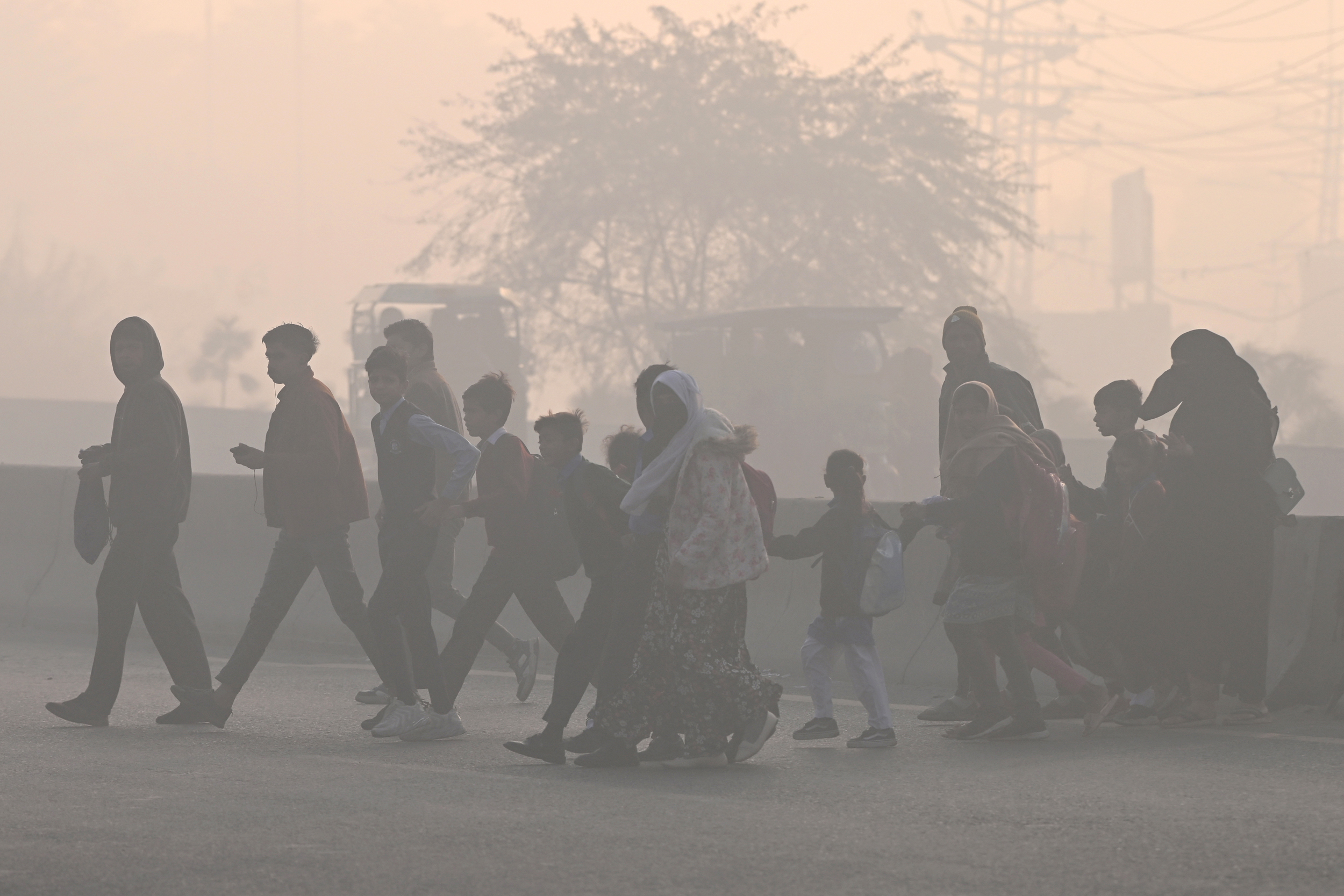 People walk across a road amid dense smog in Lahore on Dec. 12. Credit: Arif Ali/AFP via Getty Images