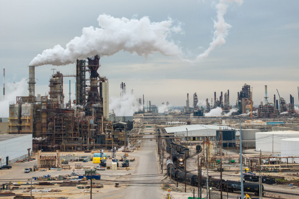 An aerial shot shows billowing white emissions from stacks in the large complex.