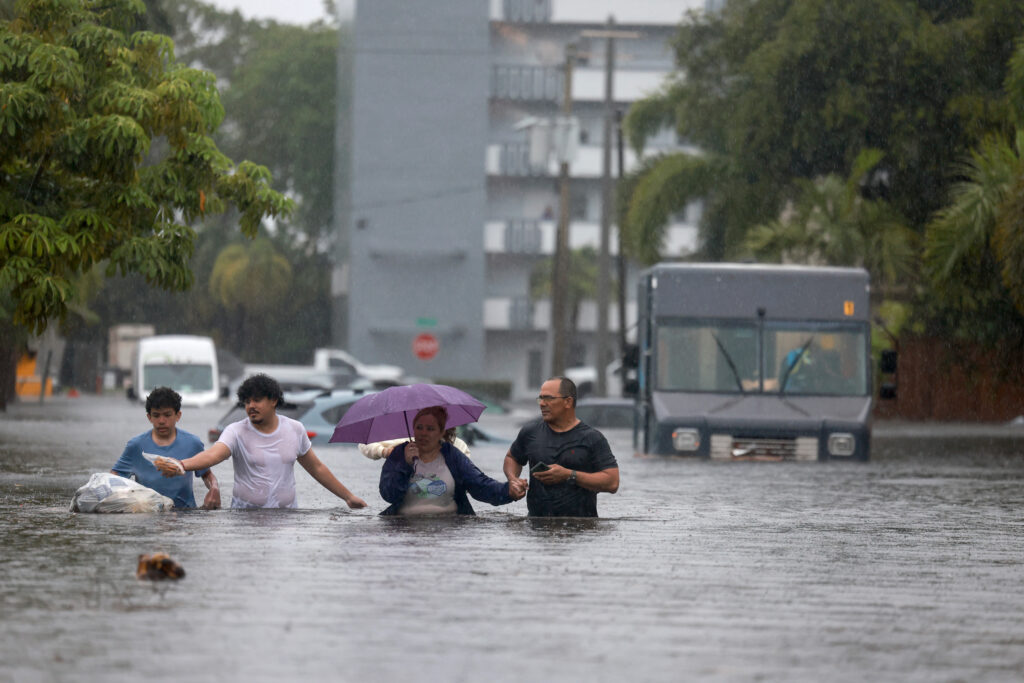 People walk through as flooded street as they evacuate during a storm on June 12, 2024, in Hollywood, Fla. Credit: Joe Raedle/Getty Images