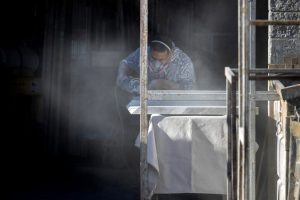 A stone countertop fabricator creates a cloud of dust while wearing a mask to help protect against airborne particles, which can contribute to silicosis, at a shop in Sun Valley, Calif. Credit: Brian van der Brug/Los Angeles Times via Getty Images