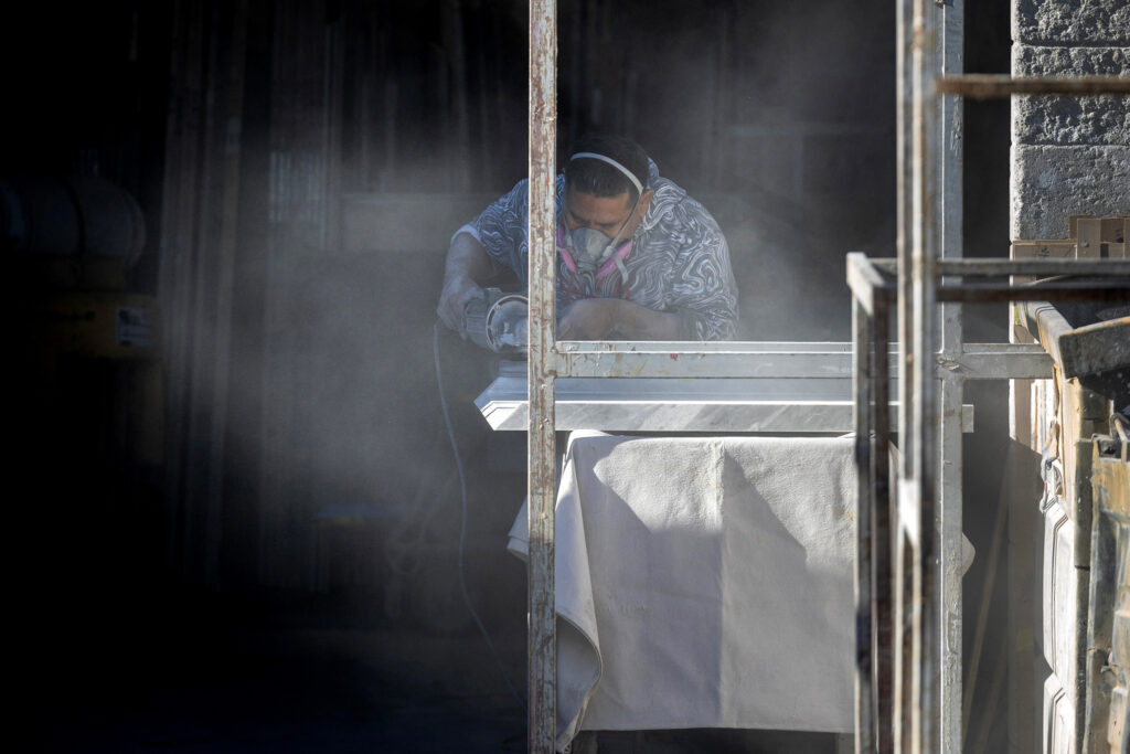 A stone countertop fabricator creates a cloud of dust while wearing a mask to help protect against airborne particles, which can contribute to silicosis, at a shop in Sun Valley, Calif. Credit: Brian van der Brug/Los Angeles Times via Getty Images