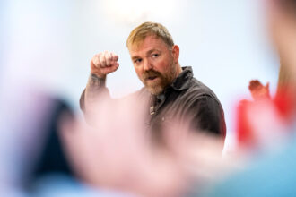 O candidato ao Senado Graham Platner fala durante um evento de campanha em 1º de maio em Portland, Maine. Crédito: Graeme Sloan/Getty Images