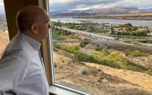 O prefeito de Dalles, Richard Mays, observa a vista de sua cidade e do rio Columbia de sua casa no topo de uma colina em The Dalles, Oregon. Os moradores de The Dalles deverão saber em breve quanto de sua água os data centers do Google têm usado para resfriar os computadores, depois que uma ação judicial que buscava manter as informações confidenciais foi arquivada.
