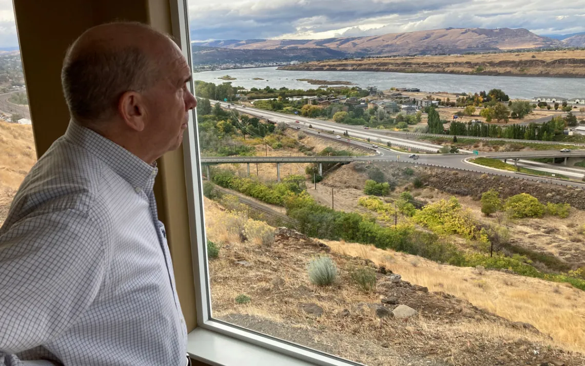 O prefeito de Dalles, Richard Mays, observa a vista de sua cidade e do rio Columbia de sua casa no topo de uma colina em The Dalles, Oregon. Os moradores de The Dalles deverão saber em breve quanto de sua água os data centers do Google têm usado para resfriar os computadores, depois que uma ação judicial que buscava manter as informações confidenciais foi arquivada.