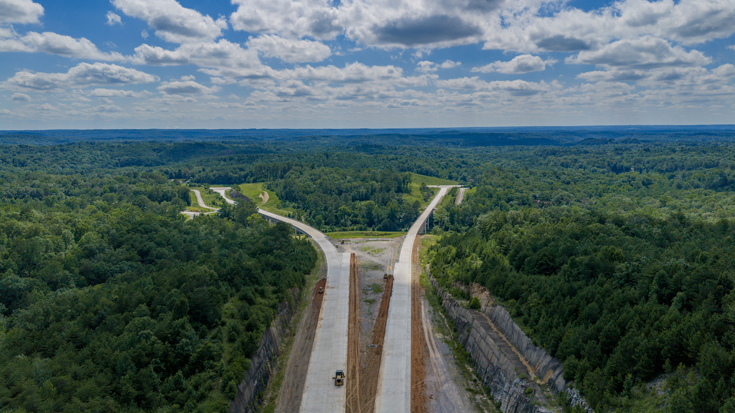 Uma foto aérea mostra a construção de uma rodovia cortando uma floresta.