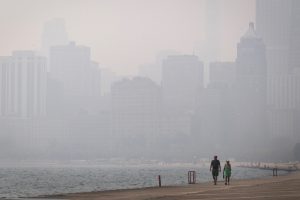 People walk along Lake Michigan as smoke from Canadian wildfires blankets Chicago on Thursday. Credit: Scott Olson/Getty Images