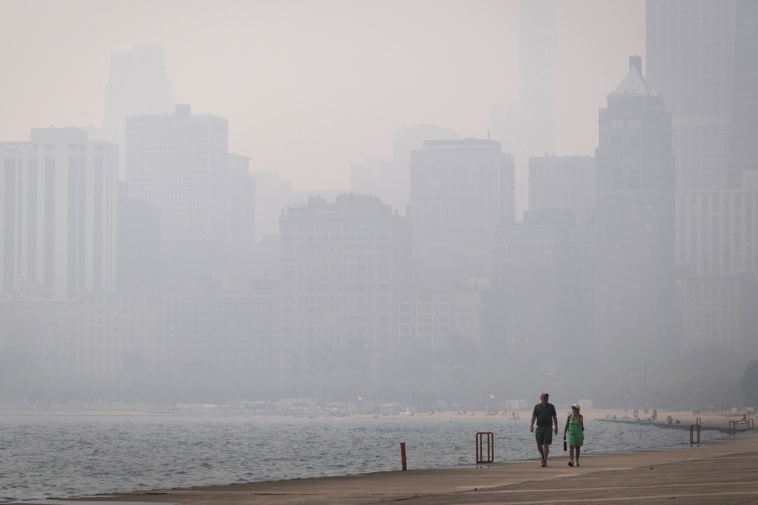 People walk along Lake Michigan as smoke from Canadian wildfires blankets Chicago on Thursday. Credit: Scott Olson/Getty Images