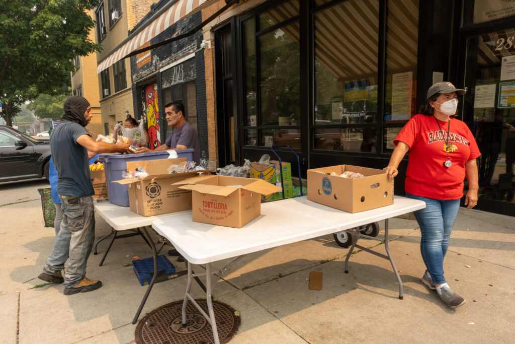 Digna Abrego (à direita) distribui mantimentos gratuitos na European American Association em Humboldt Park na quinta-feira. Crédito: Keerti Gopal/Naturlink