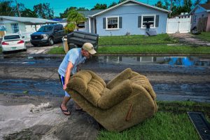 A man moves a chair in Tampa, Fla., as people remove debris and clean their homes after flooding caused by Hurricane Milton on Oct. 11, 2024. Credit: Giorgio Viera/AFP via Getty Images