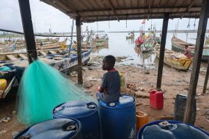 A boy sits near fishing boats in Adwoa, Ghana, on June 23. Credit: Nipah Dennis/AFP via Getty Images