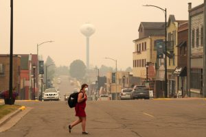 A pedestrian walks in downtown Ely, Minn., as the air is filled with smoke from multiple wildfires burning in the Boundary Waters Canoe Area Wilderness on July 15. Credit: Anthony Soufflé/The Minnesota Star Tribune via Getty Images