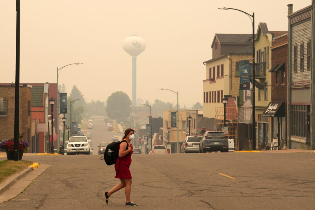 A pedestrian walks in downtown Ely, Minn., as the air is filled with smoke from multiple wildfires burning in the Boundary Waters Canoe Area Wilderness on July 15. Credit: Anthony Soufflé/The Minnesota Star Tribune via Getty Images