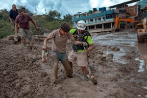 A rescuer assists a resident through heavy mud following flash floods on Aug. 27 in Trishuli, Nepal. Credit: Ezra Acayan/Getty Images