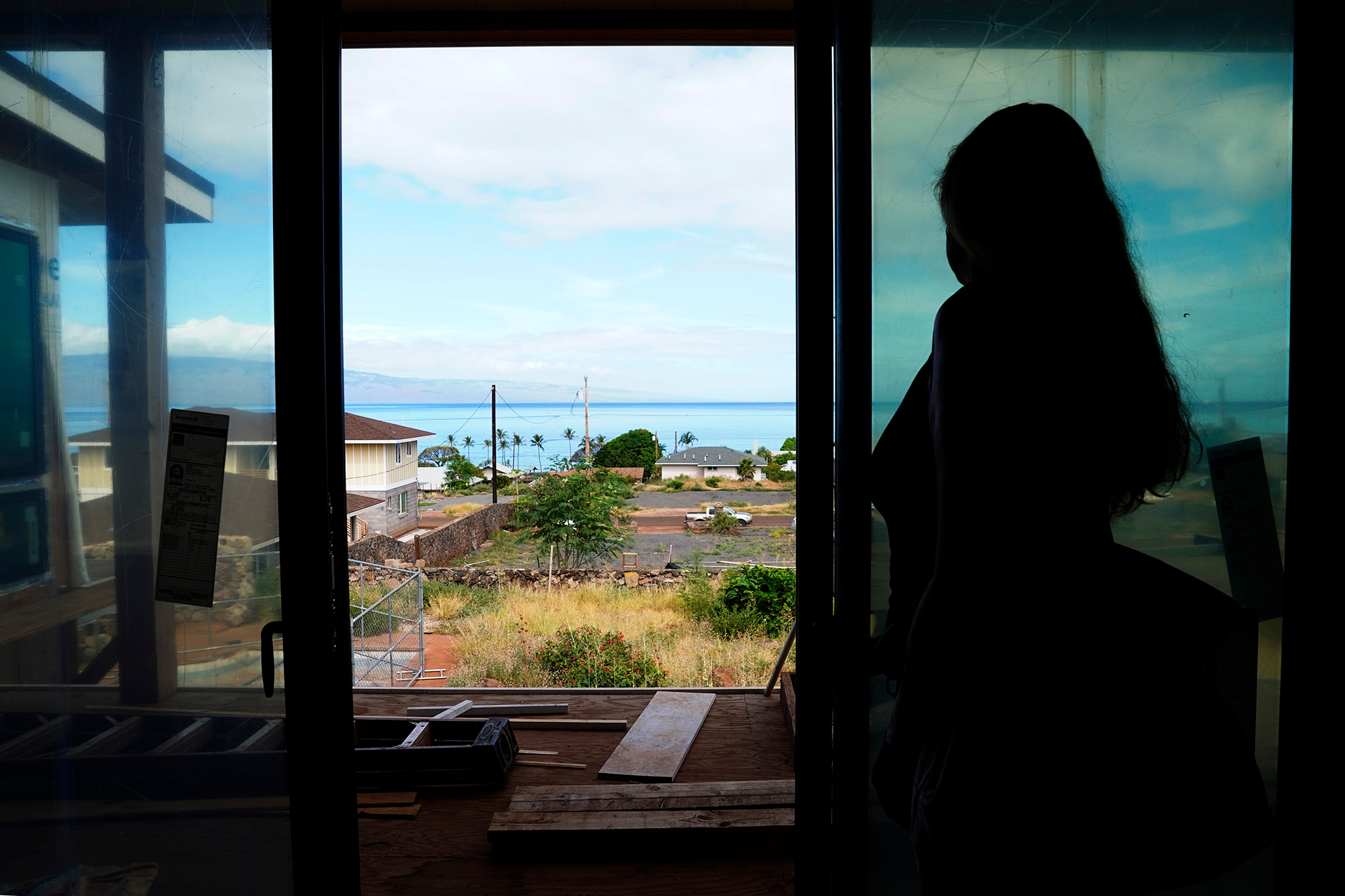 Wildfire survivor Krista Woodward opens the sliding glass door at her stalled home reconstruction on July 1 in Lahaina, Hawaiʻi. Credit: Kevin Fujii/Civil Beat