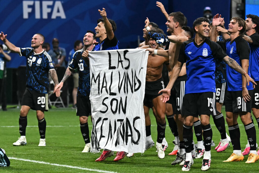 Argentina’s national team players hold a banner reading “The Malvinas are Argentine” after winning a World Cup semifinal match against England in Atlanta on July 15. Credit: Paul Ellis/AFP via Getty Images