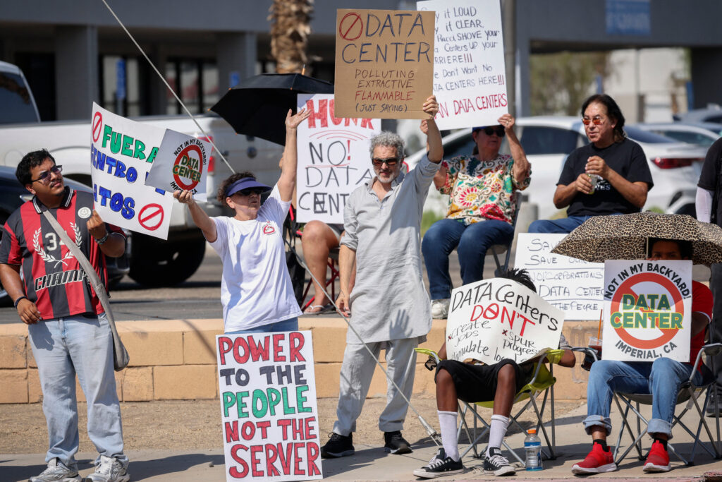 Demonstrators wave signs during a protest against AI data center development in rural Imperial, Calif., on July 18. Credit: Sandy Huffaker/AFP via Getty Images
