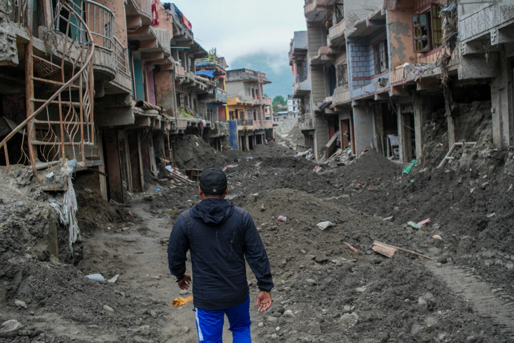 A man walks past debris from houses damaged by devastating floods in Devighat, in Nepal