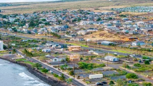 An aerial photo shows a portion of Lahaina, Hawaii, near the water. Properties are a mix of homes, houses under construction and empty lots.